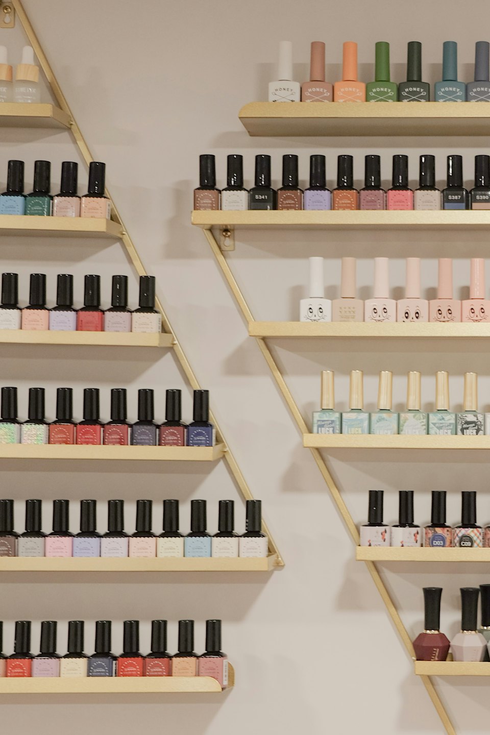 Filas de esmaltes de uñas expuestos en estantes dorados.
